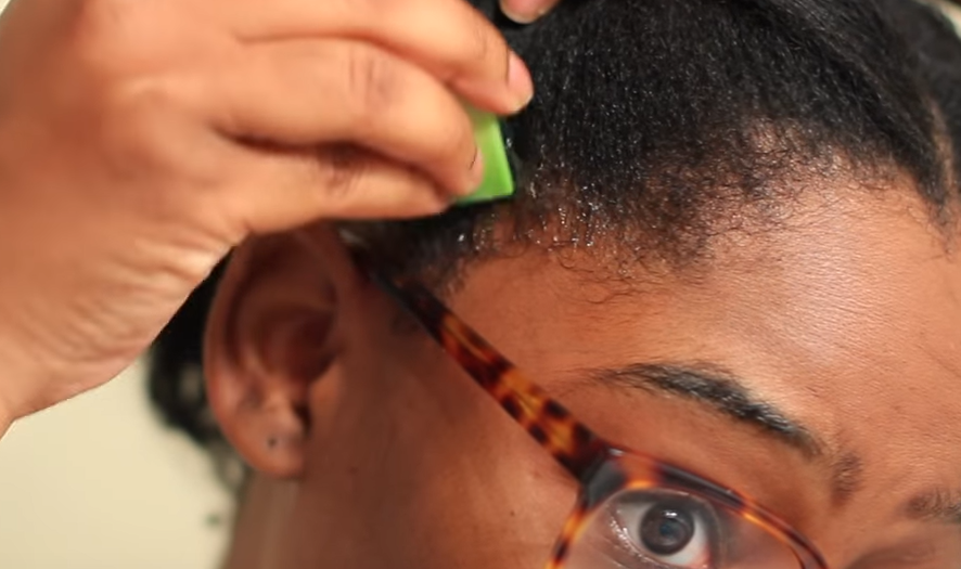 A person applying aloe vera gel to their scalp