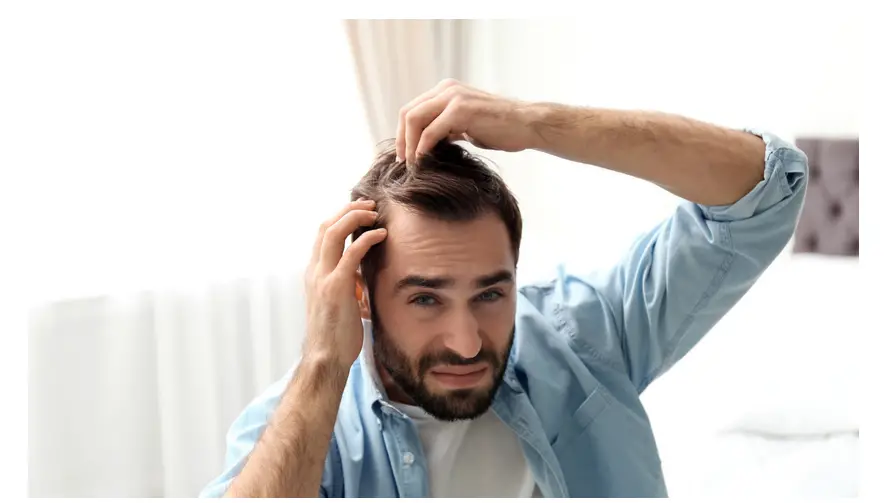 A person touching their receding hairline depicting the emotional impact of hair loss